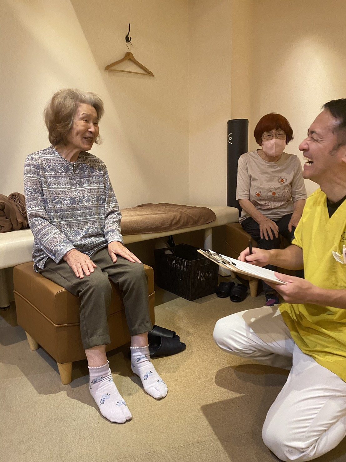 体操教室で、チェック表を手にしたスタッフと参加者が笑い合っている様子